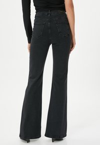 Svarta utsvängda jeans i denim med hög midja, två bakfickor och diskreta sömdetaljer. Texturerad, medeltjockt tyg.