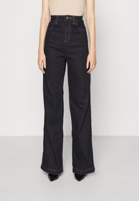 Högmidjade, vida mörkdenimjeans med gyllene sömmar och framknäppning. Har två framfickor.