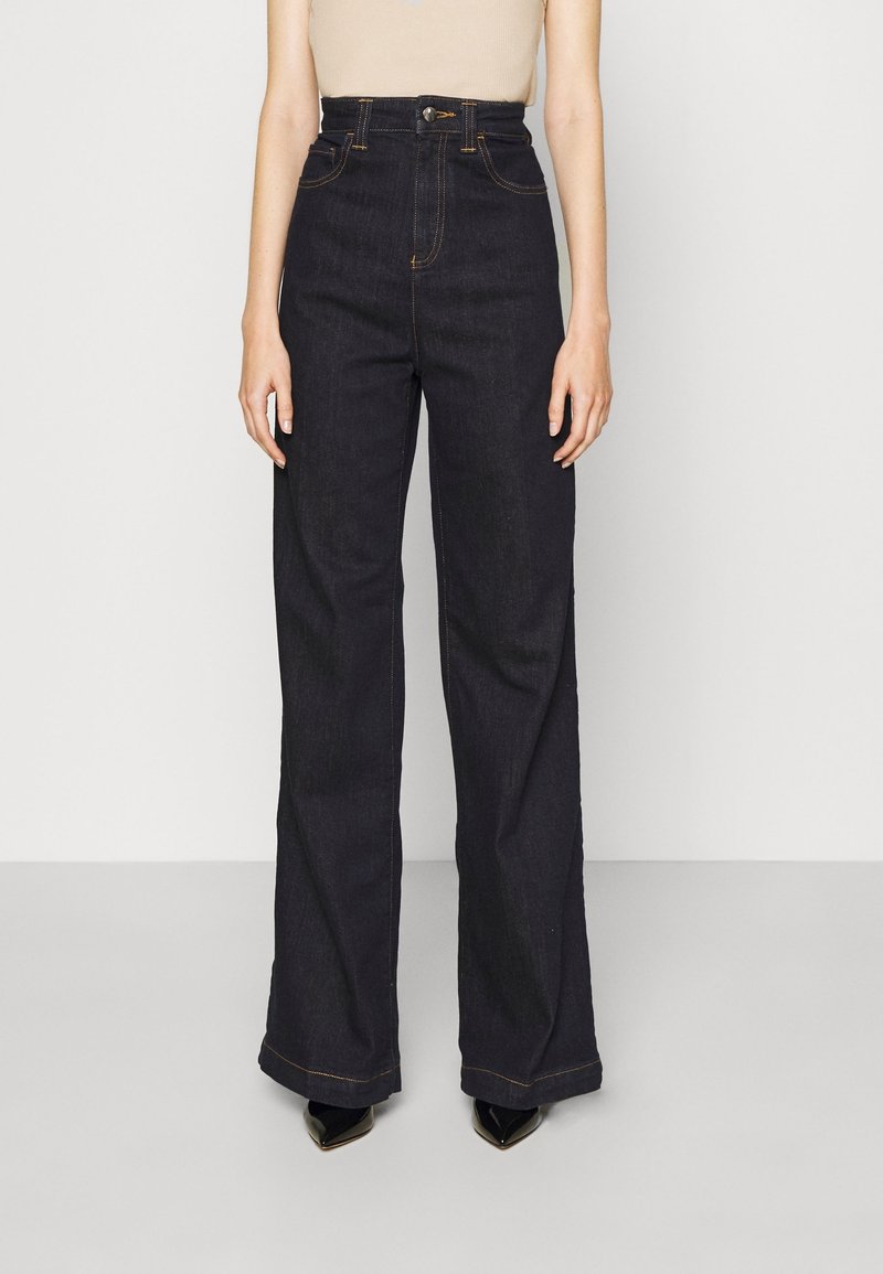 Högmidjade, vida mörkdenimjeans med gyllene sömmar och framknäppning. Har två framfickor.