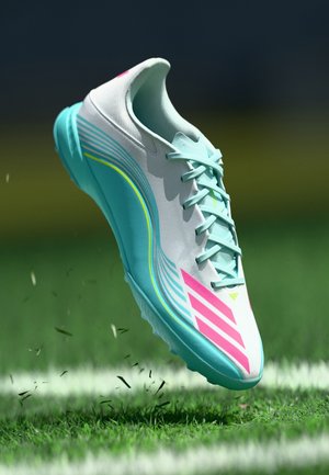 Scarpa da ginnastica azzurro chiaro con accenti rosa, superficie testurizzata e dettagli bianchi. Presenta un design aerodinamico e sei occhielli per i lacci.