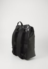 Zaino nero con materiale lucido e liscio. Caratterizzato da spallacci imbottiti e testurizzati e da una maniglia superiore per un facile trasporto.