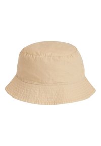 Pălărie bej de bumbac tip găleată cu o coroană rotundă și boruri largi, lăsate să cadă. Prezintă cusături subtile și un detaliu cu logo pe o parte.