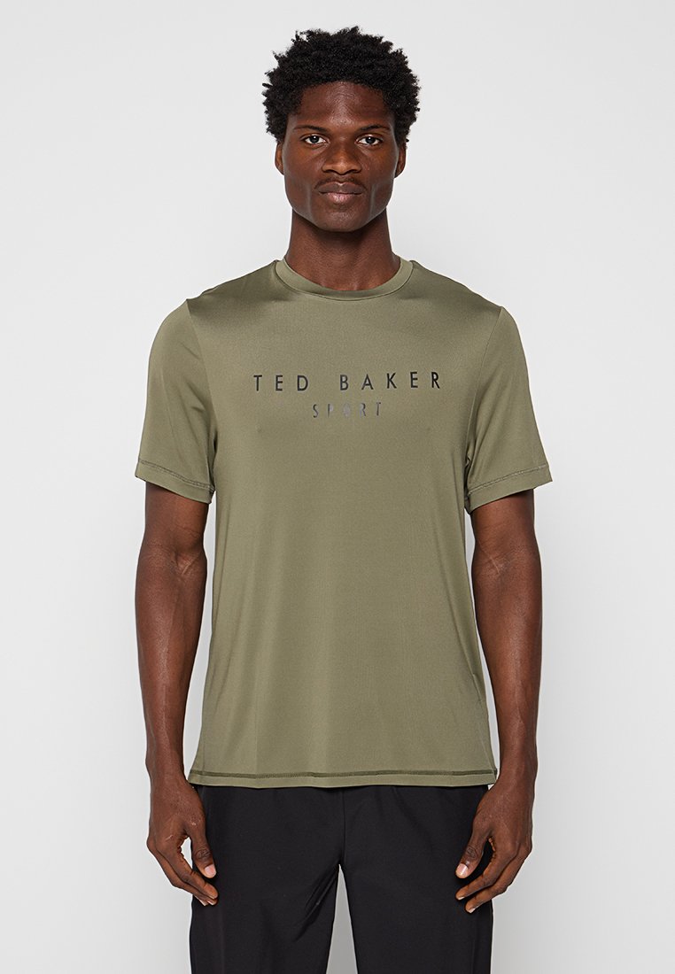 Camisa atlética de manga corta color verde oliva con cuello redondo y logo negro "TED BAKER SPORT" en el pecho. Material suave y ligero.