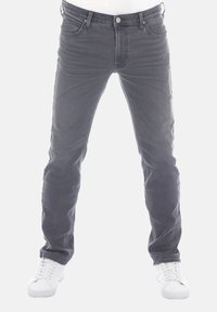 Jeans in denim grigio con vestibilità slim, design a cinque tasche e finitura sbiadita. Presentano una chiusura con bottone e cuciture a contrasto. Sneakers bianche.