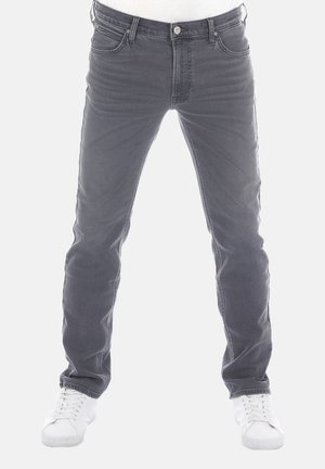 Vaqueros de mezclilla gris con corte ajustado, diseño de cinco bolsillos y acabado desgastado. Cuenta con un cierre de botón y costuras contrastantes. Zapatillas blancas.
