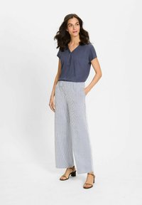 Marineblauw T-shirt met korte mouwen en V-hals; lichtgestreepte, wijdvallende broek; bruine sandalen met blokhak; gladde texturen overal.