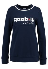 Marinblå sweatshirt med långa ärmar, vit rund halsringning och centralt placerad Reebok Classic-logotyp i vitt och rött. Mjuk, texturerad bomullsmaterial.
