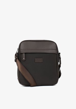 Petit sac bandoulière marron foncé avec dessus en cuir texturé, corps en tissu, bandoulière réglable et écusson logo à l'avant.