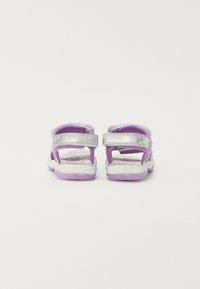 Lila Sandalen mit silbernen Riemen, verstellbaren Verschlüssen und gemusterten Innensohlen. Dicke weiße und lilafarbene Sohlen bieten Dämpfung und Unterstützung.