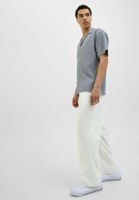Cămașă ușoară, cu mânecă scurtă, gri cu un model, cu guler, asortată cu pantaloni largați albi și adidași albi.