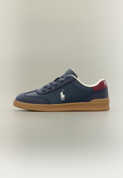 Μπλε σκούρο Polo sneaker με λαστιχένια σόλα, λευκό λογότυπο στο πλάι, μπορντό ταμπάκι στη φτέρνα και λευκή εσωτερική επένδυση, εμφανίζεται σε πλευρικό προφίλ.