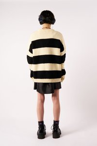 Megzta megėklė su juodais ir kreminiu horizontaliais dryžiais, didelio dydžio, stambus tekstūra, ruoželinės apykaklės, derinama su juoda satino sijonu ir stambiais batais.