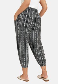 Pantalones con estampado en blanco y negro, de corte relajado, con puños ajustados, cinturilla elástica y bolsillos laterales. Tejido suave con estampado geométrico.