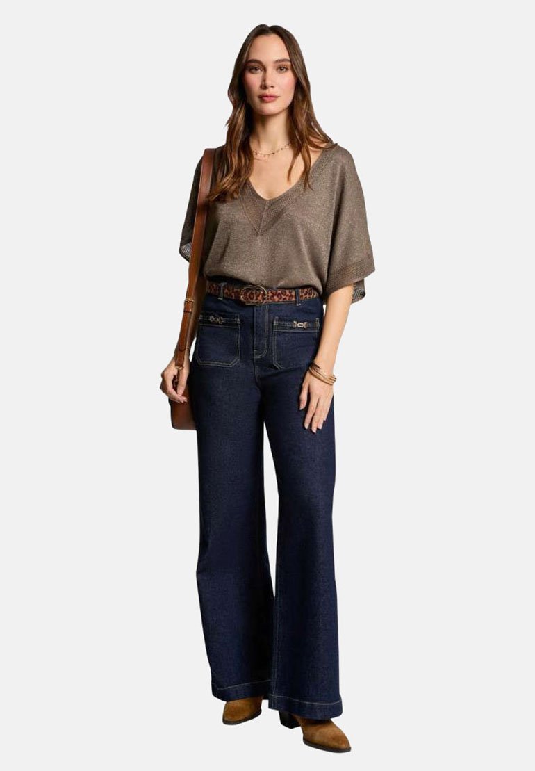 Top metallico di taglio ampio in bronzo, abbinato a pantaloni flared in denim scuro a vita alta e una cintura in stampa animale marrone. Stivaletti marroni.
