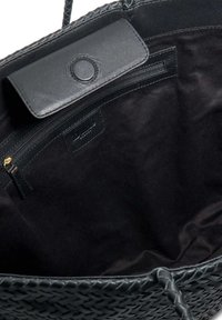 Black woven leather tote bag with a smooth black leather flap, interior zip pocket, and soft fabric lining. Interior is spacious and dark.
