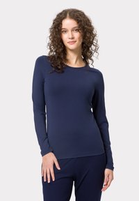 Haut à manches longues bleu marine en tissu lisse et extensible. Il présente un col rond et une silhouette ajustée, associé à un pantalon bleu marine assorti.