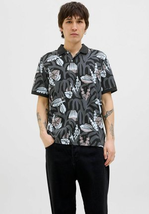 Kortærmet, sort polo-shirt med et livligt plantebaseret mønster i nuancer af blå, pink og creme. Blød tekstur, klassisk kravedesign.