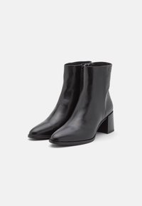 Bottes cheville en cuir noir avec bout pointu, talon bloc, fermeture éclair latérale et design épuré ; panneau arrière texturé pour un détail supplémentaire.