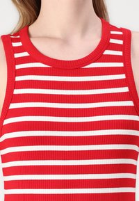 Débardeur côtelé avec un motif rayé rouge et blanc. Doté d'un col rond et d'une conception sans manches. Texture de tissu douce et extensible.