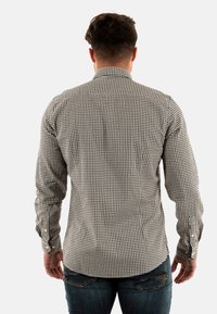 Zwart-wit geblokte shirt met lange mouwen en knopen, met een puntige kraag en een gebogen zoom, gezien vanaf de achterkant.
