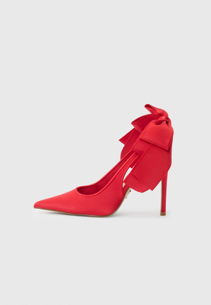 Chaussure à talon haut en satin rouge avec un bout pointu et un grand nœud décoratif sur le talon, présentant un design découpé et un talon aiguille.