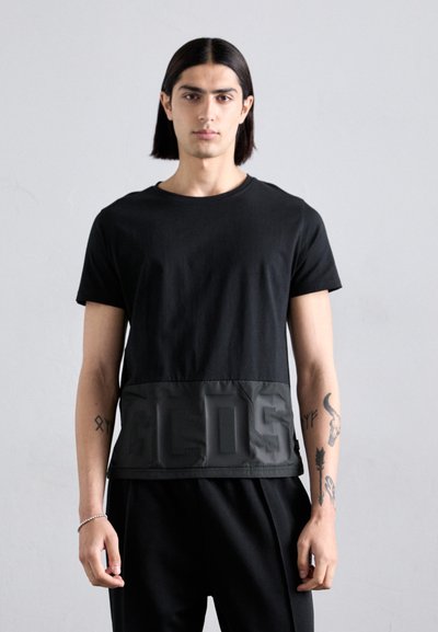 Zwarte t-shirt met een matte bovenkant en een glanzend onderpaneel met reliëftekst. Korte mouwen, ronde halslijn, gemaakt van een katoenmix.