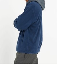 Fleecejacka i marinblått, med långa ärmar, huva och sidoficka. Mjuk textur med avslappnad passform och något förlängd rygg.
