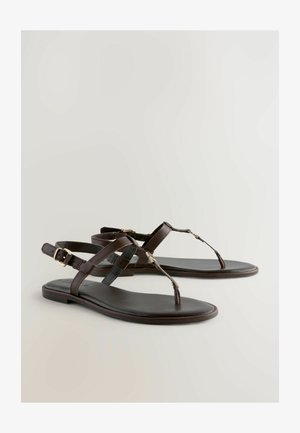 Sandales plates en cuir marron avec un entre-doigt, des sangles croisées et une boucle réglable. Surface lisse et design minimaliste.