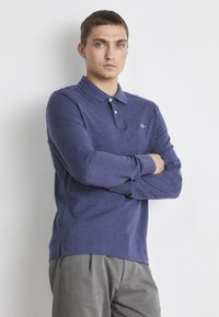 Navyblaues Langarm-Polohemd aus weicher Stoffqualität, mit Kragen, drei Knöpfen und seitlichen Schlitzen am Saum.