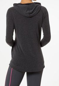 Grau, langärmliger Hoodie mit lockerer Passform, ausgestattet mit einer Vordertasche und einer Hood mit Kordelzug. Das Material wirkt weich und hat eine glatte Textur.