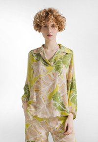 Løs, langærmet bluse i let, blomsterprintet stof. Indeholder nuancer af grøn, gul og beige med en krave.