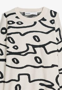 Bežna pulover s bold črnimi abstraktnimi vzorci, z okroglo izrezom in strukturiranim pletenjem. Oznaka vidna: BERSHKA.