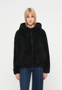 Μαύρο μπουφάν με κουκούλα από μαλακό, υφασμάτινο ύφασμα με φερμουάρ μπροστά και άνετη γραμμή. Διαθέτει φαρδιά μανίκια και αδόμητο σχέδιο.