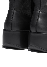 Zwarte leren enkellaarzen met een gladde textuur, voorzien van een ronde blokhak en een minimalistisch ontwerp, met zichtbare naaddetails.