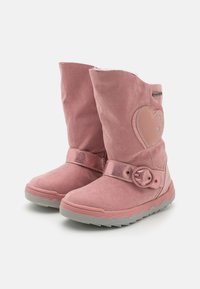 Růžové semišové boty s srdcovým detailem, kovovým páskem a přezkou a texturovanou šedou podrážkou s vlnitým okrajem.