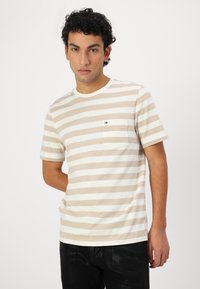 Striped t-shirt in beige and white, featuring short sleeves, a round neckline, and a left chest pocket with a small logo detail.