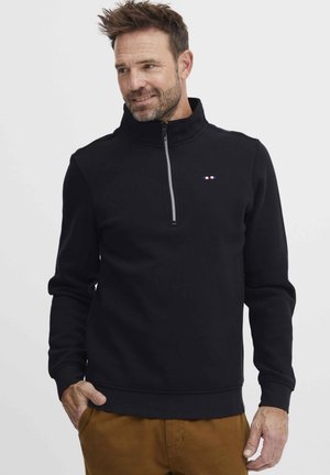 Felpa nera con zip e collo alto realizzata in tessuto morbido; presenta un logo discreto in rosso, bianco e blu sul petto; polsini e orlo a coste.