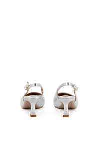 Scarpe con tacco in metallo argentato, con punta rotonda, cinturino alla caviglia e un modestissimo tacco a blocco. Texture liscia e design minimalista.