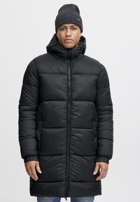 Abrigo puffer negro con capucha, que presenta un diseño acolchado y cierre de cremallera. Puños de canalé, dos bolsillos laterales y una textura suave.