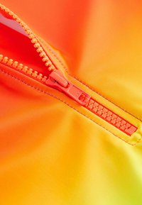 Lys orange stof med en gradient til gult, der har en central plastiklynlås med en matchende trækflig og kontrasterende stikninger.