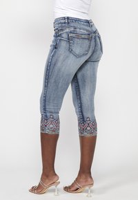 Hellblaue Denim-Capris mit dekorativen bestickten Mustern am Saum. Verfügt über standardmäßige Taschen und einen figurbetonten Schnitt.