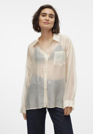 Lett, semi-transparent kremknappskjorte med lange ermer, lomme detaljer og subtile grå aksenter. Stylet med mørke jeans.
