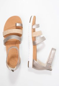 Sandały na otwartym palcu z metaliczno-srebrnymi i korkowymi paskami, beżowa, wyściełana wkładka, biała podeszwa i zamek błyskawiczny z tyłu, pokazane z góry i z boku.