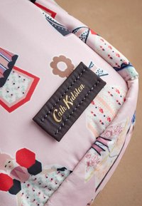 Ružová textilná taška s kvetinovým a cupcake vzorom, s hnedou štítkom embosovaným "Cath Kidston" a modrým prešitím.