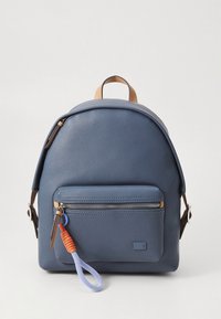 Mėlyna odinė kuprinė su apvaliomis formomis, priekyje yra kišenė užtrauktuku, rudos spalvos akcentai. Pagaminta iš tekstūruotos medžiagos, su spalvotu užtrauktuko laikikliu.