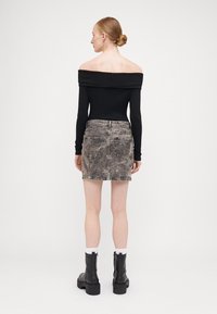 Svart avtakbar ribbet topp kombinert med en falmet denim miniskjørt med baklommer og frynset kant. Svart chunky hæl støvler.