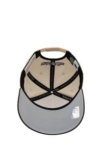 Casquette avec une visière grise et un corps beige, intérieur doublé de tissu noir et présentant des coutures décoratives, étiquettes visibles sur la couronne intérieure.