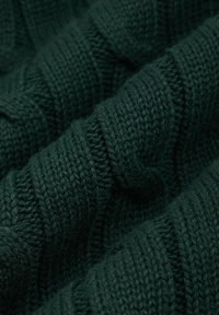 Ciemnozielona dzianina o fakturze z żebrowanym wzorem. Przędza wydaje się miękka i gruba, ukazując szczegółowe przeszycia.