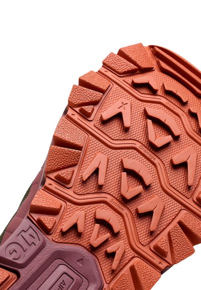 Gros plan d'une semelle de chaussure de randonnée orange et violette avec un motif de crampons texturé et multidirectionnel et la marque "ATG".