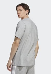 Camiseta de manga corta gris de algodón, con un corte relajado y textura suave. La parte de atrás presenta un detalle de costura mínima.
